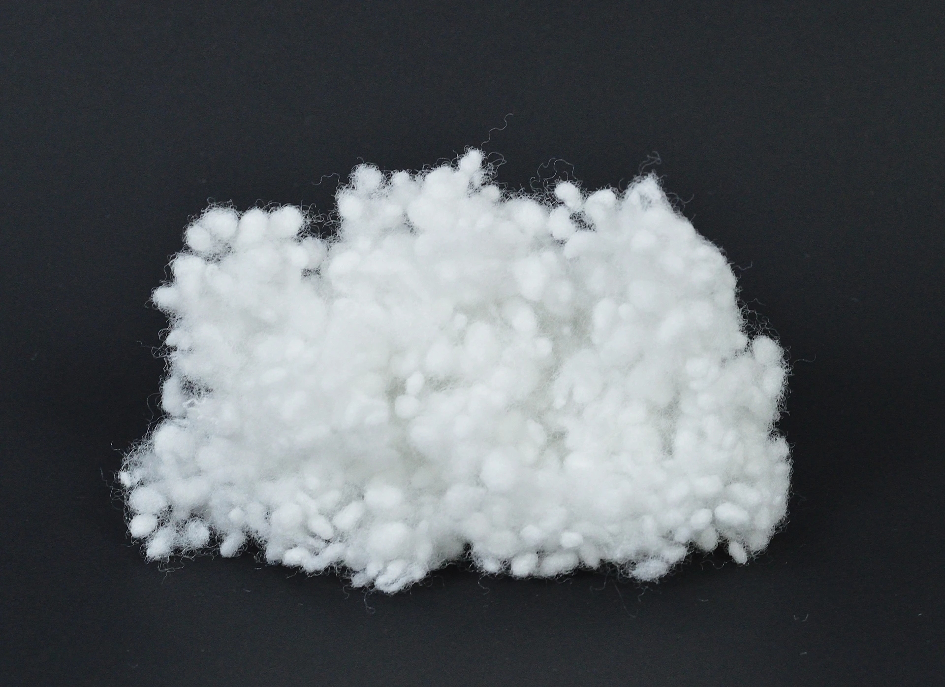 White Unicurl fibre clusters against a dark background